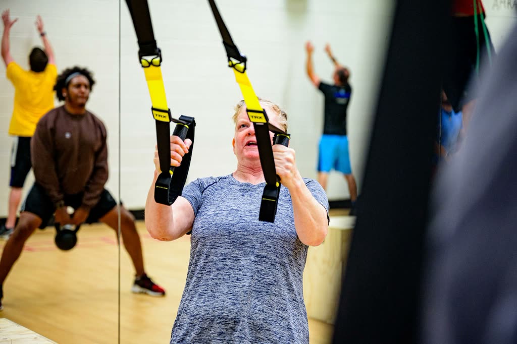 Members training with suspension straps in a group class